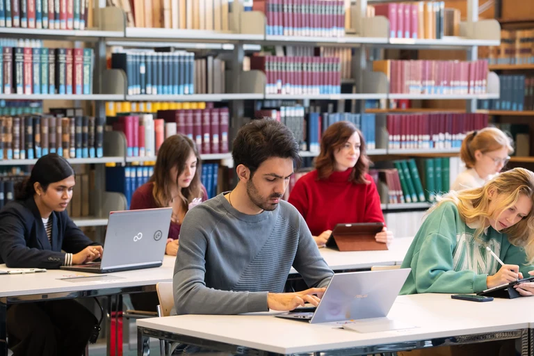 Studierende mit Laptops in Bibliothek