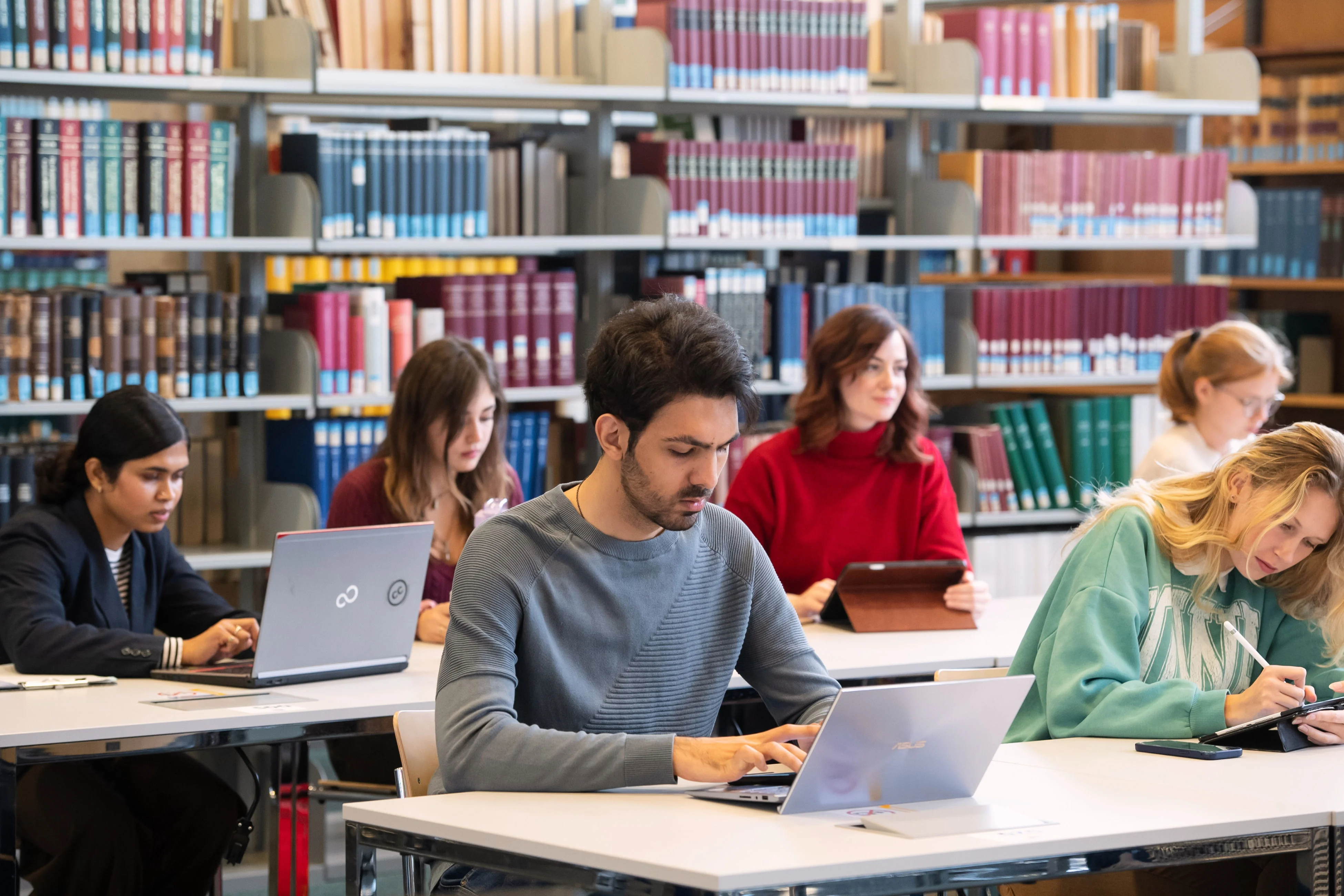 Studierende mit Laptops in Bibliothek